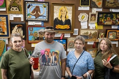 Four people pose in front of crop art