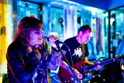 Two musicians perform onstage in a nontraditional music venue