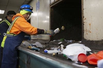 A woman throws a plastic bottle in a chute.