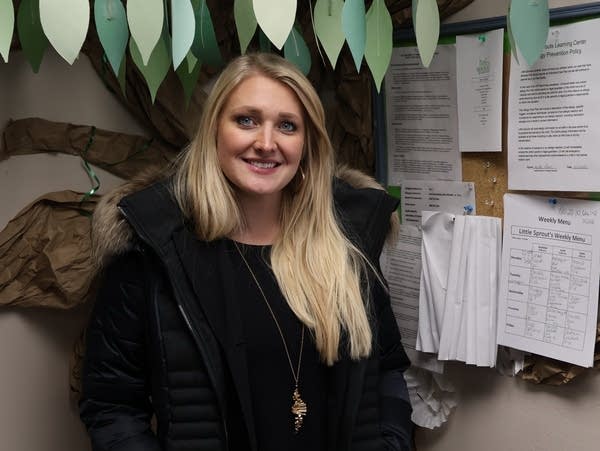 a woman stands next to a bulletin board