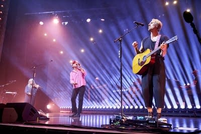 A band performing onstage in a large music venue