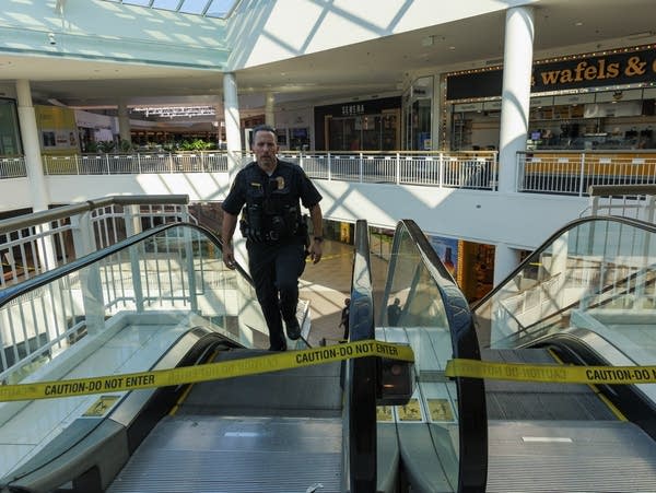 A police officer walks up an escalator 