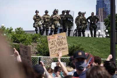 A large group of people gather holding signs.