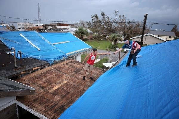 Louisiana residents install a tarp over a damaged roof in the wake of Hurricane Ida. Roofs are a key component in safety but are vulnerable to extreme weather.