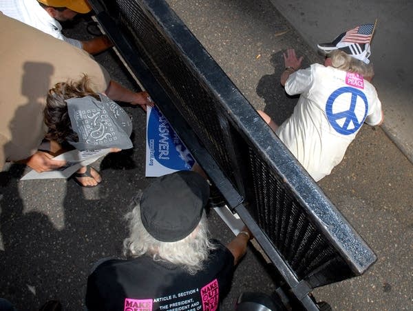 A protester crawls under a security fence