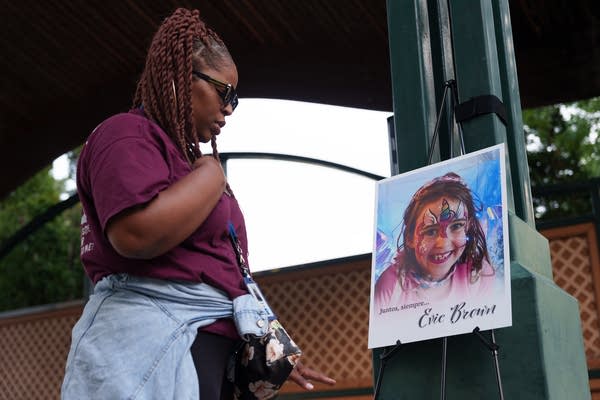 A woman looks at a photo portrait of a young girl at a vigil.