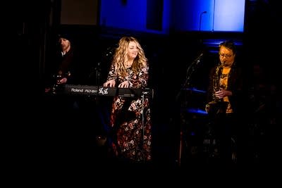 Three musicians perform together onstage