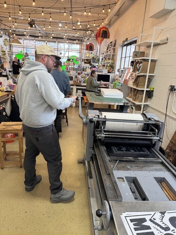 A man stands near a letter press.