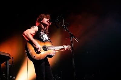 A musician sings and plays guitar onstage