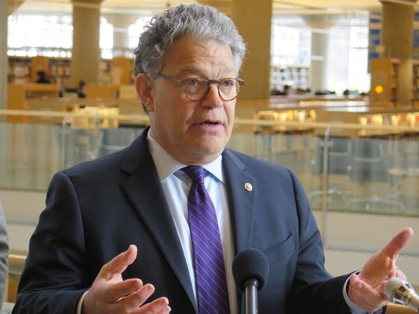 Al Franken stands in front of microphones