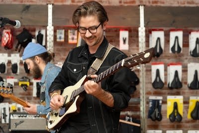 Man wearing glasses playing guitar
