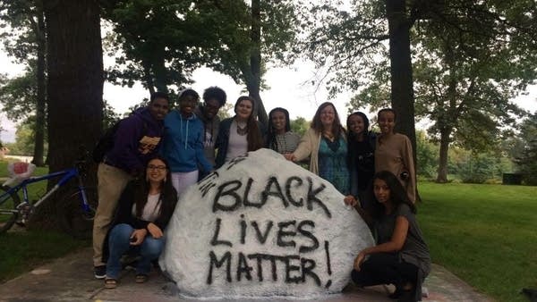 A group of students stand by a rock