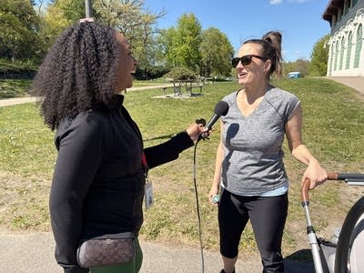 Two women smile and talk outside at a park
