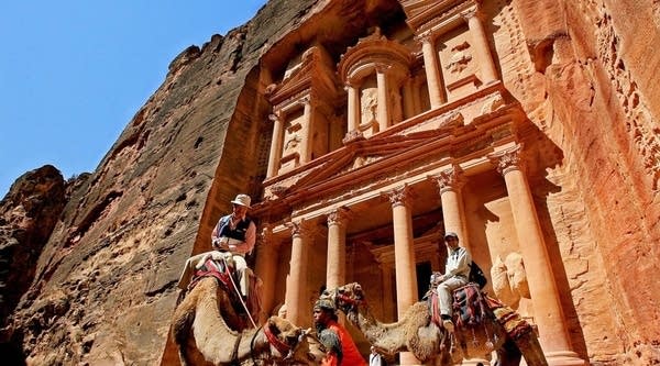 Tourists ride camels at the ancient ruins of Petra in Jordan.