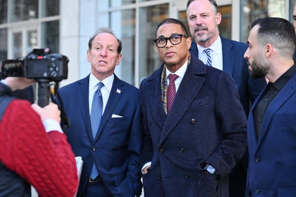Men in suits speak with reporters on the steps of a courthouse.