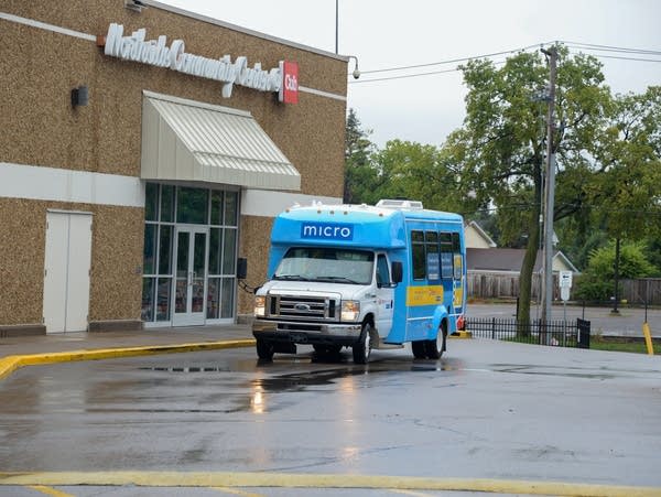 a blue and white shuttle van pulls away from a store