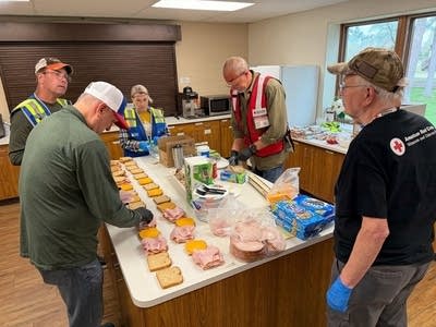 People prepare sandwiches in a kitchen.