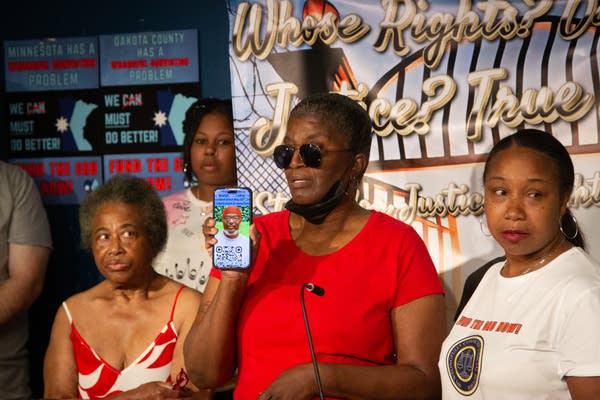 A person in a red shirt holding a photo 