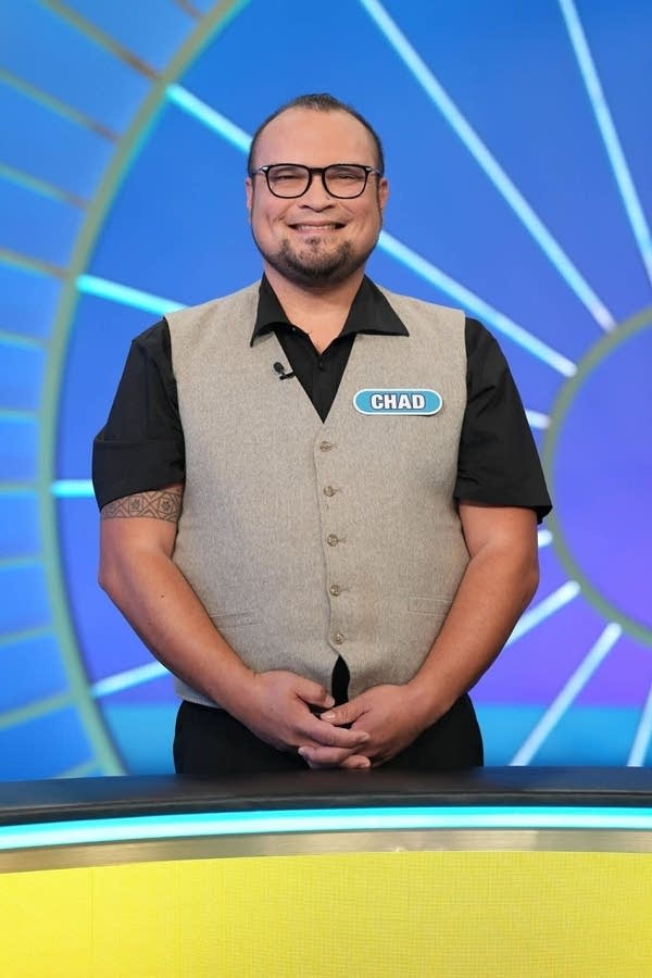 a man poses for a photo on a game show set