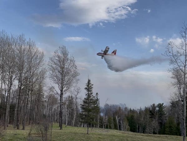 A plane drops water on a wildfire