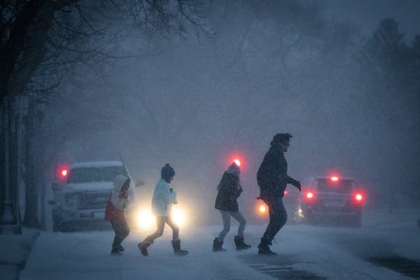 People dash across the street during a snowstorm.