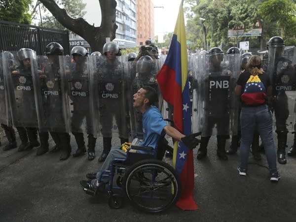 A demonstrator yells at members of the Venezuelan National Police