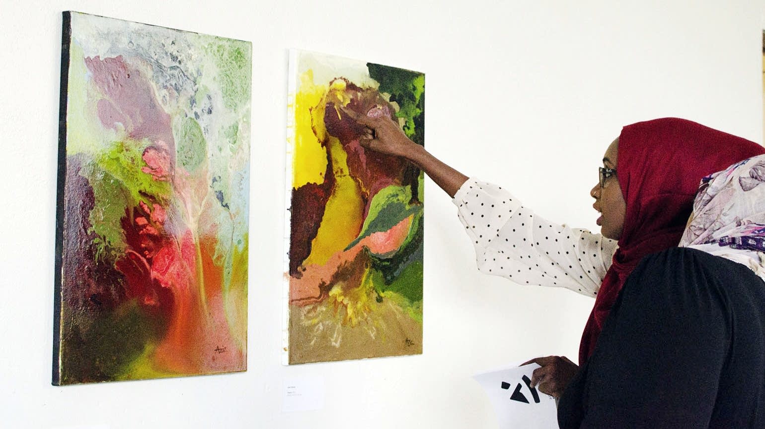 Jihan Ali and a friend examine abstract paintings.