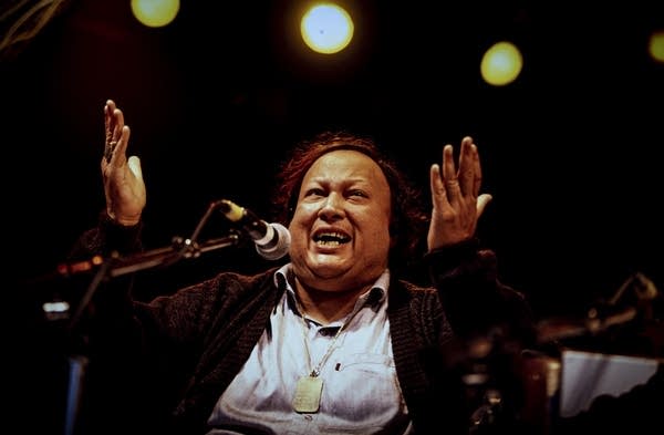 A musician sings and gestures onstage during a concert