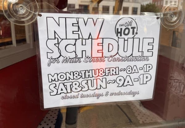 A sign displaying reduced hours for The Cafe HOT during construction.