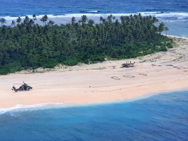 "SOS" message dug into sand on a remote beach w/ rescue chopper on site