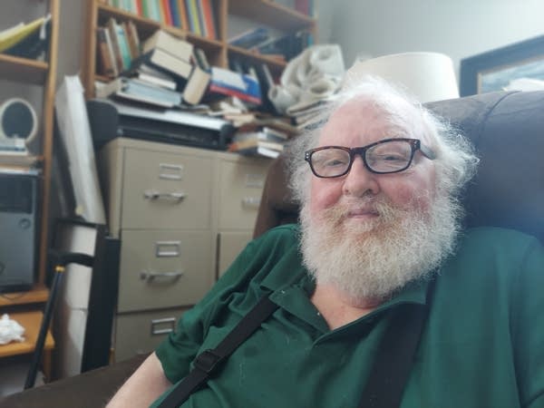 Man with white beard and glasses posing for photo in his office