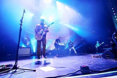 A band performing onstage in a large music venue 