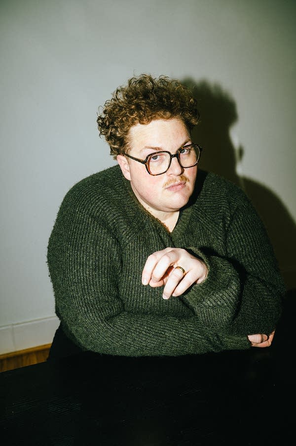A man in glasses and a sweater sits casually at a table