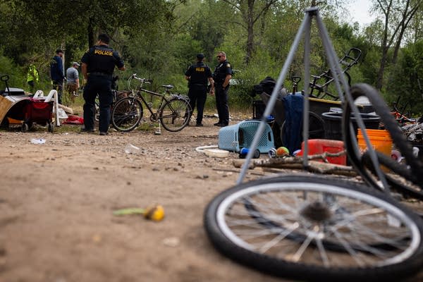 Police officers stand in a homeless encampment