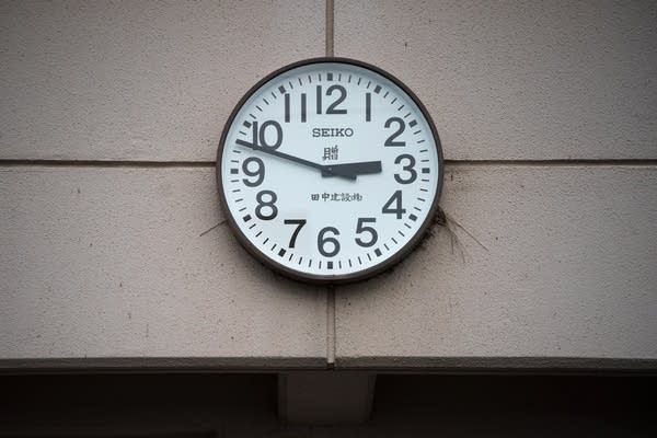 A round analog clock on a wall, with a white face, black numbers, hands and black rim. The hands indicate 2:48.