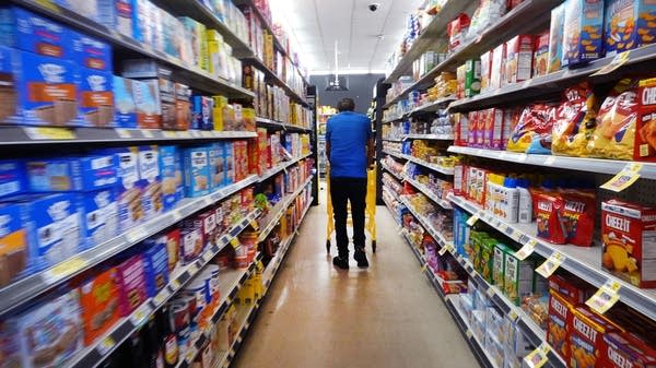A person shops in a packaged food aisle of a grocery store.
