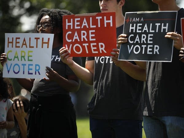 Demonstrators hold signs as Democratic leaders speak