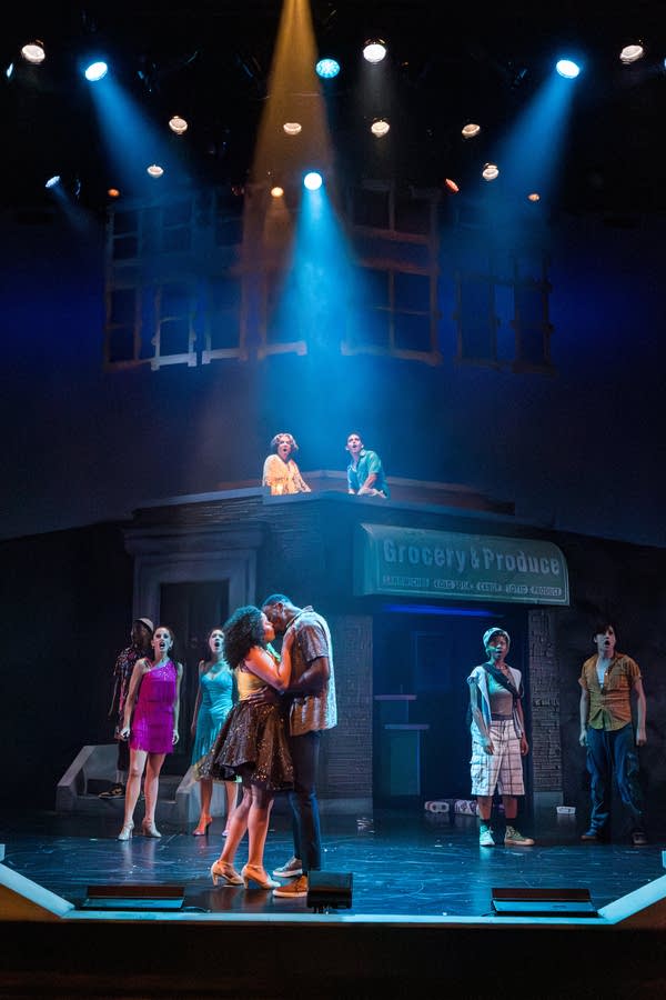 Actors perform on a stage cast in blue light.