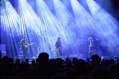 A band performing onstage in a large music venue 
