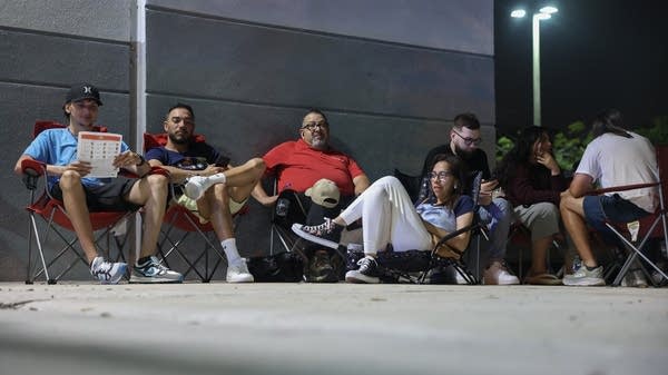 Gamers sit in camping chairs, lined up and waiting to purchase Nintendo Switch 2 consoles.
