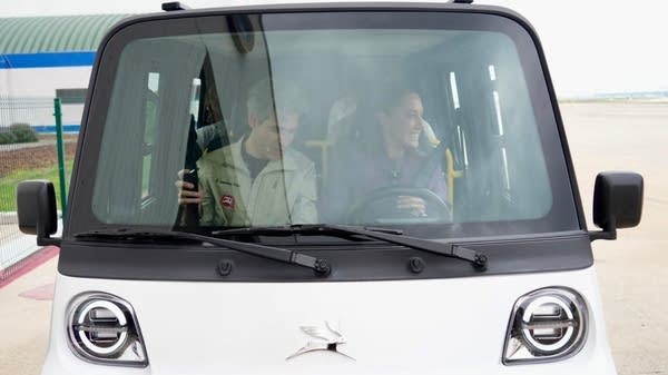 Two people smile while driving an Olinia car.