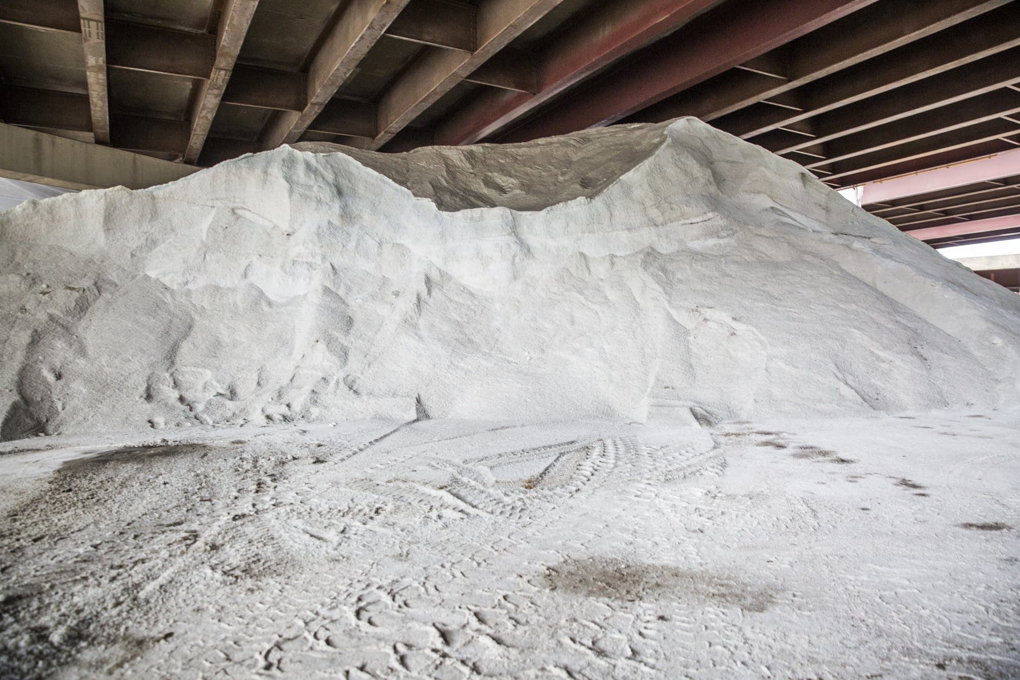 A pile of road salt sits underneath an overpass.
