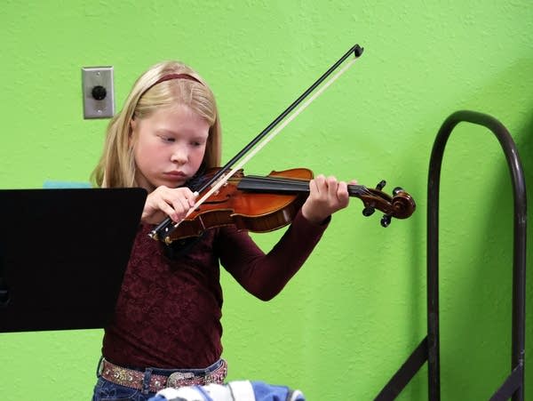 a young girl plays a violin