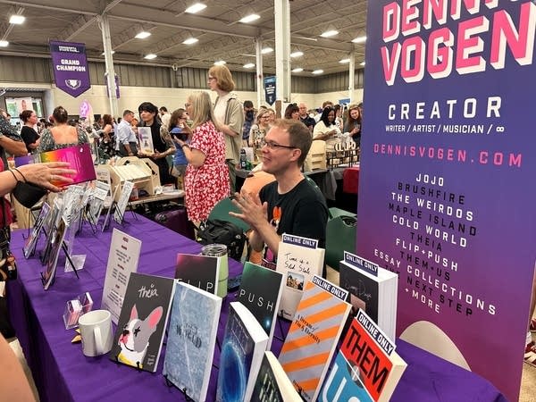 An author sits at a table with a number of books on display.
