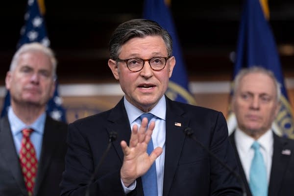 Mike Johnson speaks to press, his right hand held out.