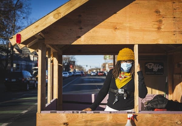 A woman stands inside a wooden structure. 