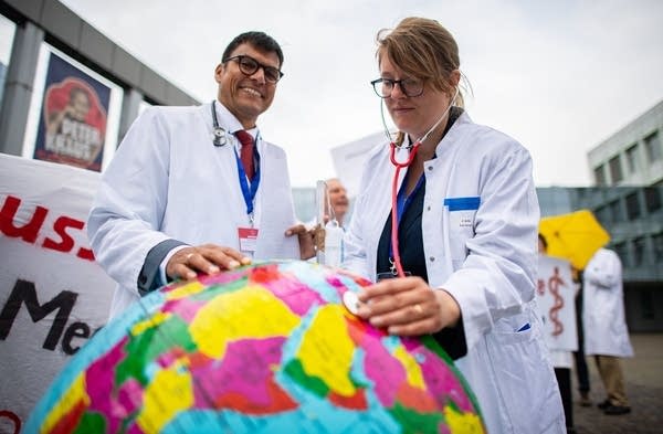 Two representatives from the organisation "Doctors For Future" use a stethoscope during a demonstration for fossil-fuel phase out and a better climate protection in Muenster, northwestern Germany (Photo: Getty Images).