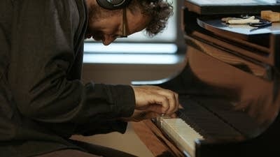 A musician plays piano in a recording studio