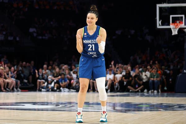A basketball player in a dark blue uniform celebrates near center court.