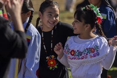 Girls smile and dance together at an Indigenous Peoples Day celebration.
